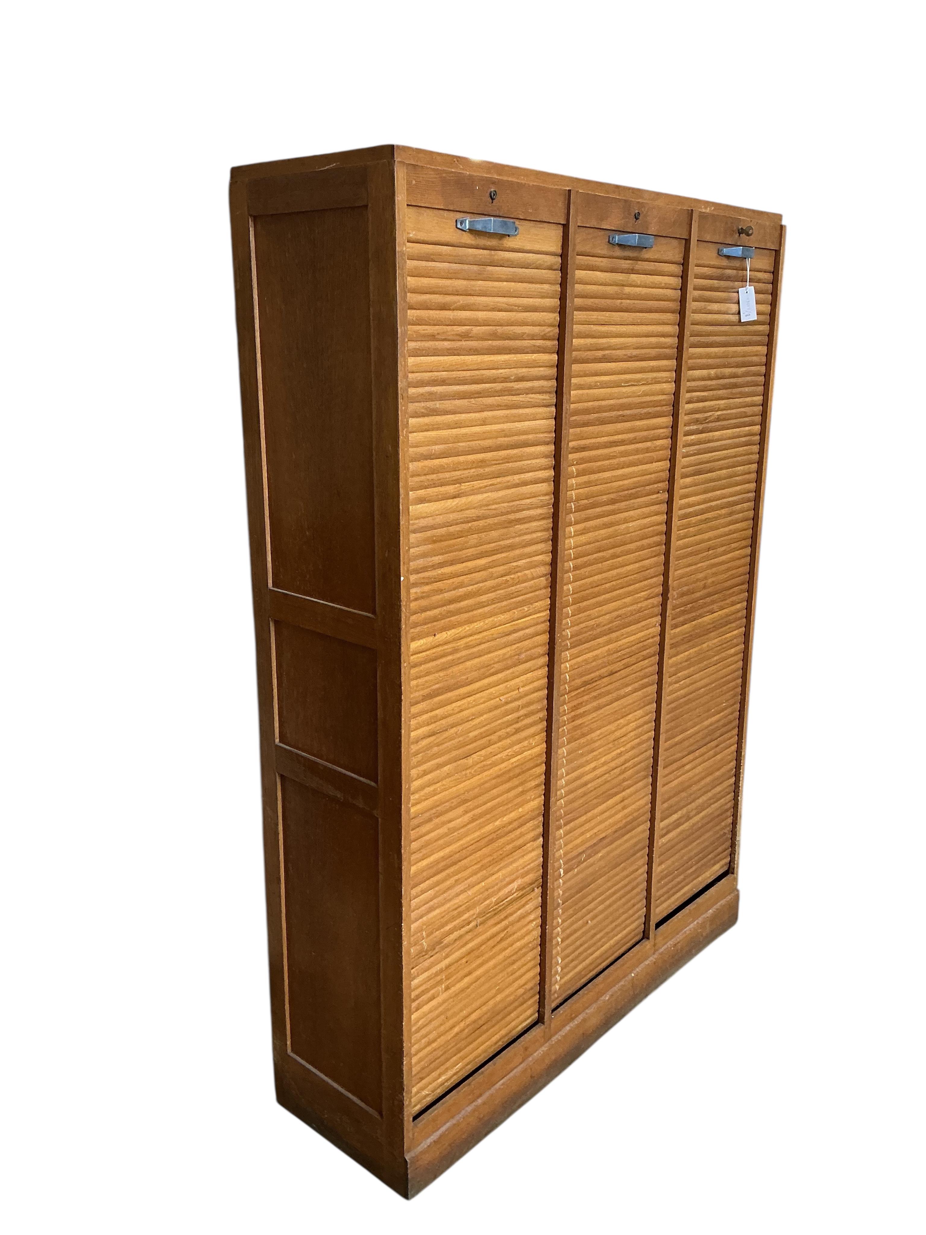 A mid 20th century oak triple tambour filing cabinet, width 126cm, depth 38cm, height 180cm
